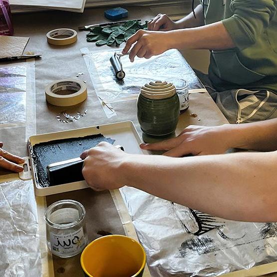 People at table using printmaking tools and ink to create art